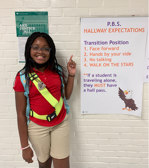 Student crossing guard pointing out Hallway Expectations sign