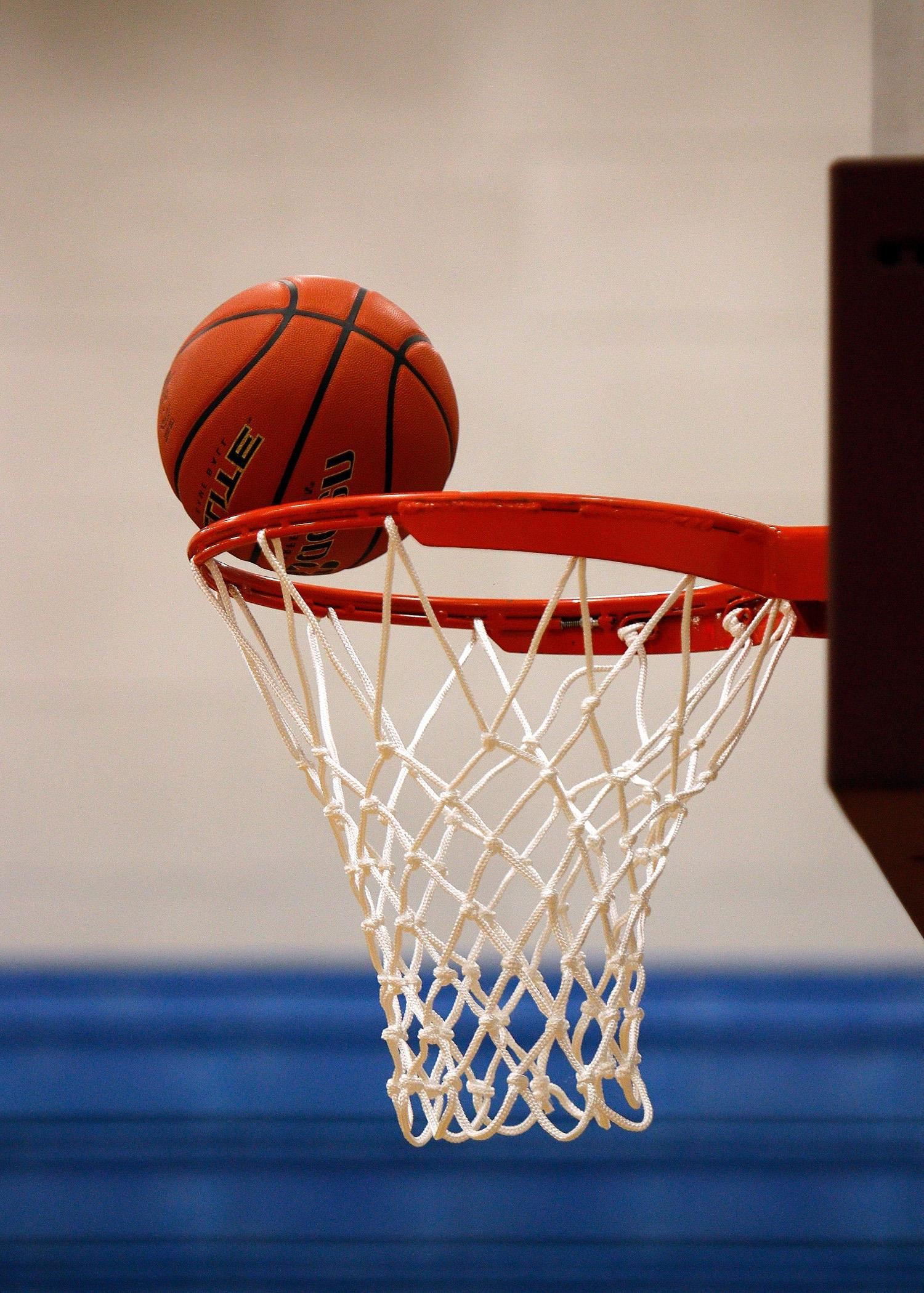 Basketball teetering on the rim of the goal